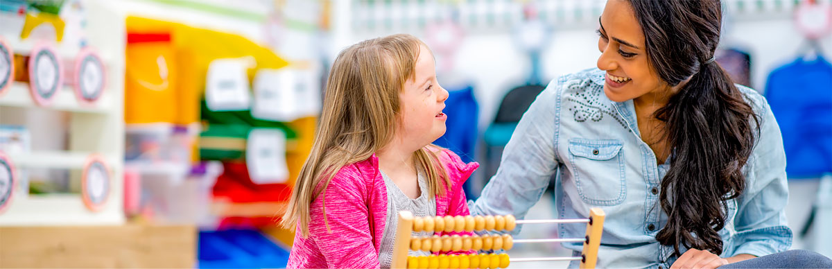 Student looking in microscope while teacher watches