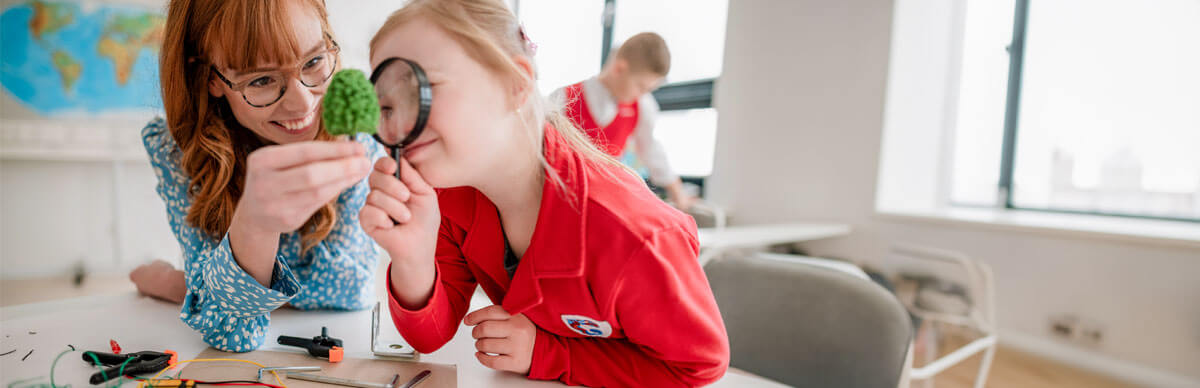 Student looking in microscope while teacher watches